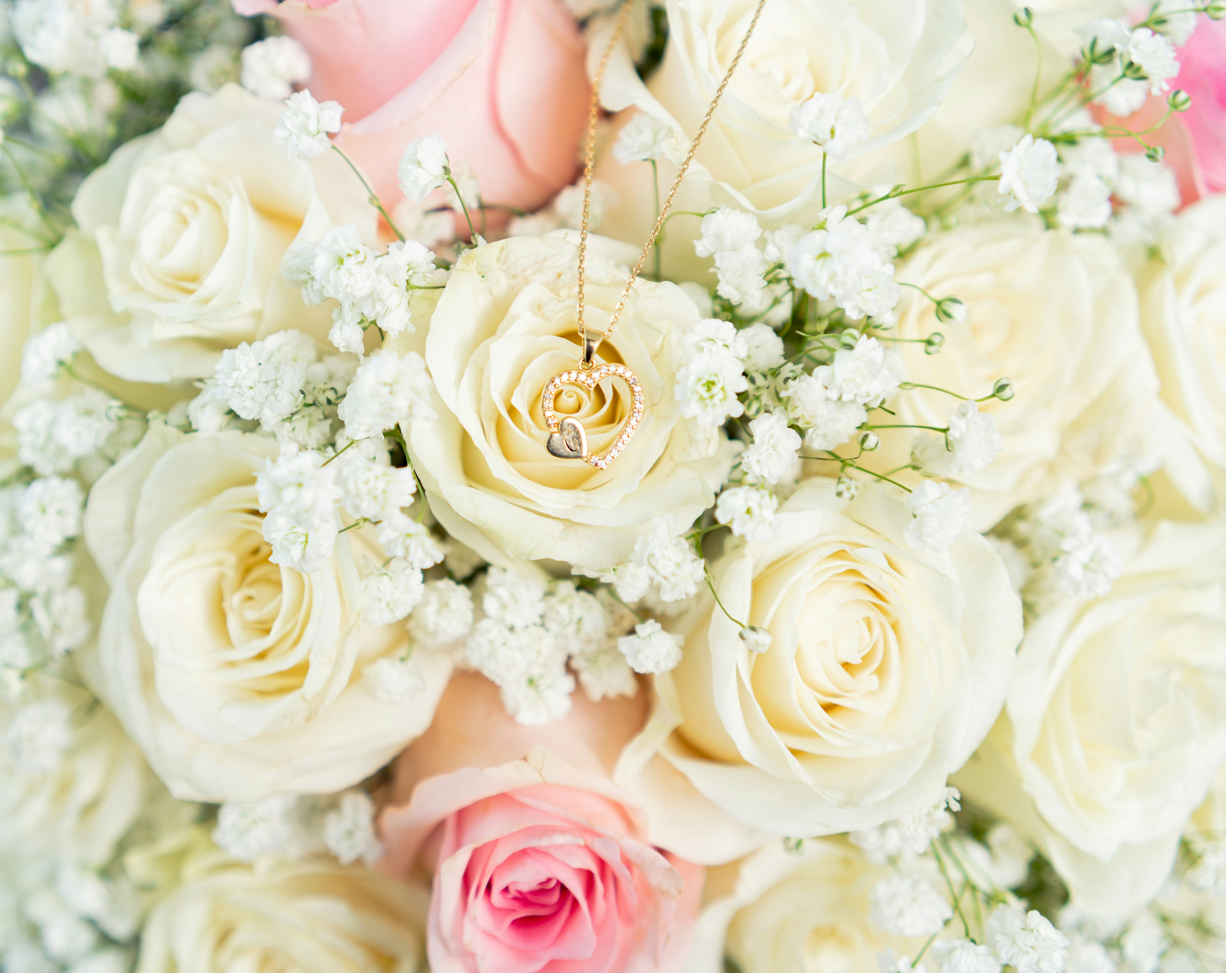 Lush white and pink rose bridal bouquet with gold necklace